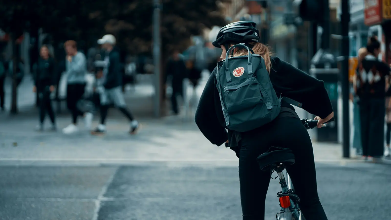 Cyklist med ryggsäck på väg genom staden
