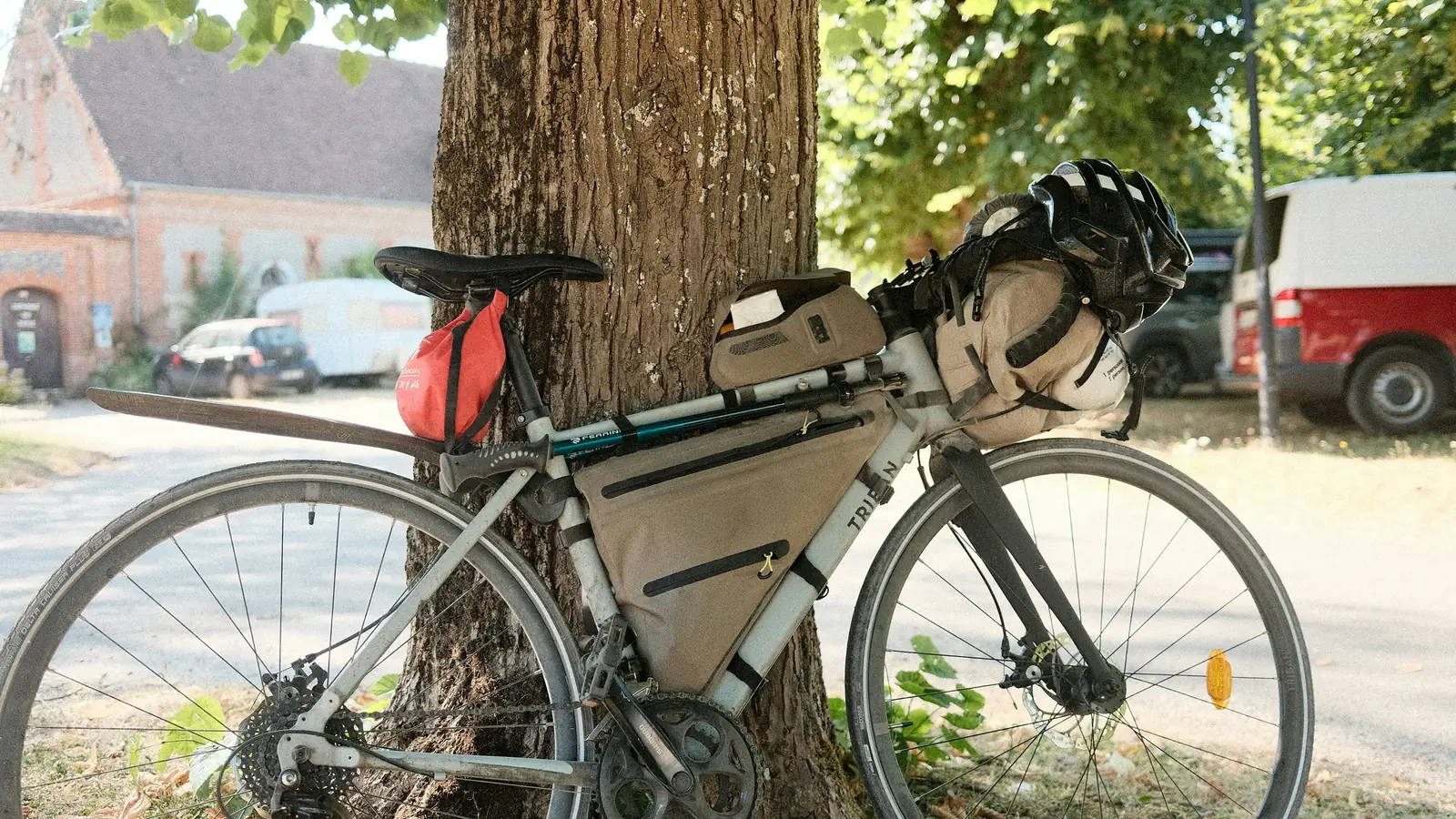 Cykel utrustad med packväskor lutad mot ett träd